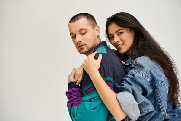 Красивая молодая пара в модной одежде обнимает друг друга, излучая любовь.