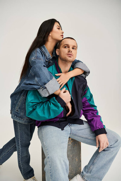 Красивая пара обнимает друг друга в модном наряде, запечатлевая момент романтики.