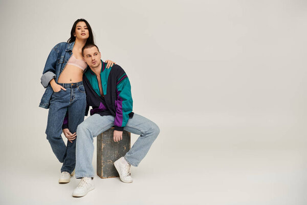 A beautiful young couple dressed in trendy outfits showcases their affection in a chic studio.