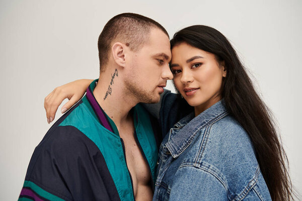 Красивая молодая пара разделяет интимный момент в стильной одежде, празднуя свою любовь.