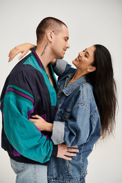 Красивая молодая пара в стильных нарядах обменивается любящими взглядами в студии.