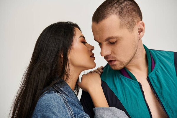 Красивая молодая пара в стильной одежде обнимается в студии.