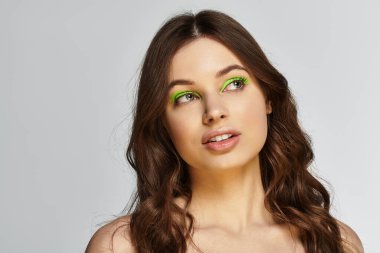 Çarpıcı yeşil göz farı olan genç bir kadın stüdyo ortamında cesur tarzıyla büyülüyor..