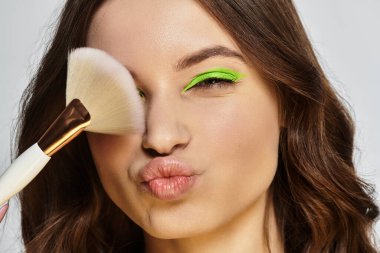 Young woman playfully showcasing her vibrant green eyeshadow under studio lights. clipart