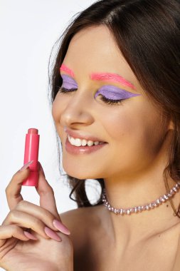 A young woman showcases her creativity with striking purple eyeshadow and pink eyebrows in a studio. clipart