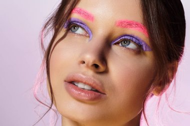 Güzel bir genç kadın, kendine has makyaj tarzını parlak renklerle gri bir arka plana vurgular..