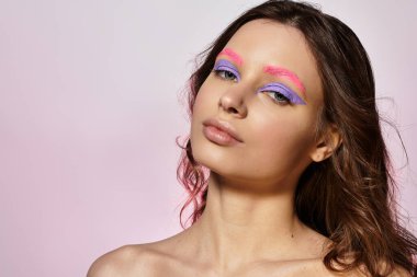 Genç bir kadın, yaratıcılığını cesur bir makyajla ve parlak renklerle gri bir zeminde sergiliyor..