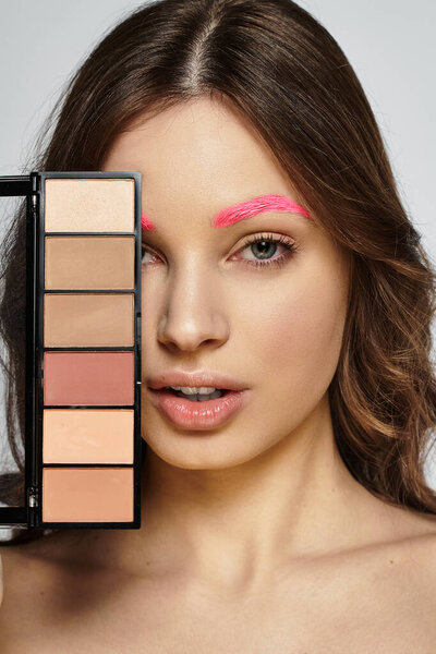 Уверенная женщина демонстрирует яркие розовые брови в шикарной художественной студии.