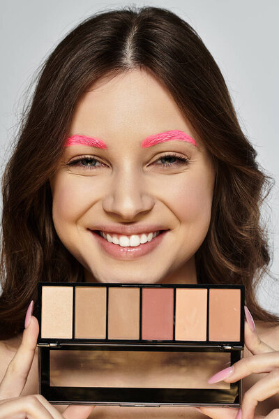 Привлекательная молодая женщина демонстрирует свои яркие розовые брови и красоту в студии.