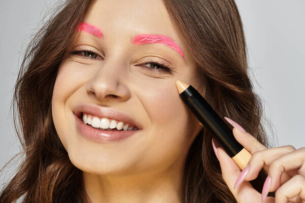 Молодая женщина подчеркивает смелый стиль и уникальные розовые брови, позируя уверенно в студии.