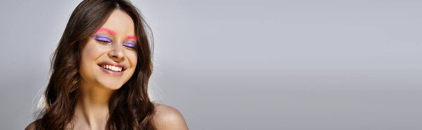 Молодая женщина демонстрирует смелый макияж с потрясающими фиолетовыми тенями для век и розовыми бровями, баннер