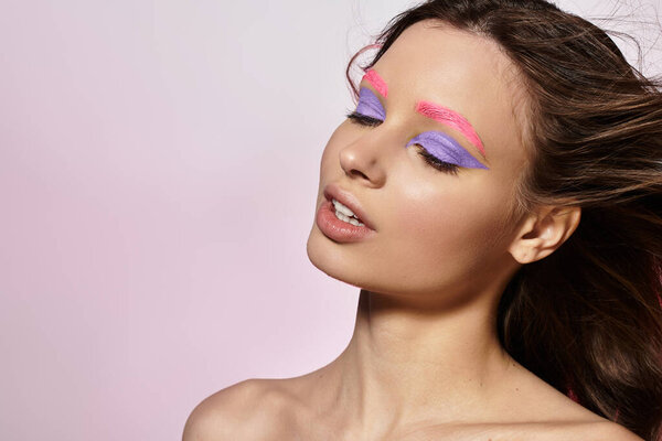 Молодая женщина демонстрирует свою поразительную красоту с смелым макияжем в студии.