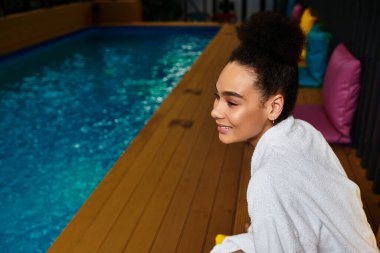 Güzel, genç bir kadın, bir spa havuzunun yanında rahatlar. Huzuru ve kaygısızlığı kucaklar..