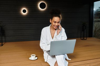 Genç bir kadın laptopuyla çalışırken ve çayını yudumlarken bir anlık huzurun tadını çıkarıyor..