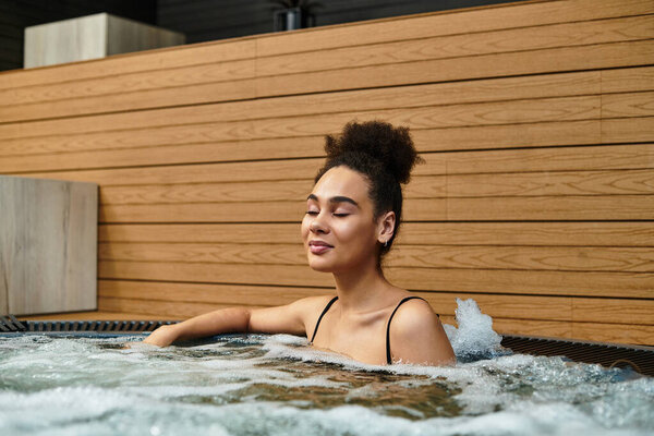 A young African American woman enjoys relaxation in a bubbling spa, embracing peace and wellbeing.