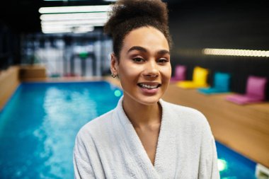 A young African American woman smiles with joy while enjoying a spa day filled with relaxation. clipart