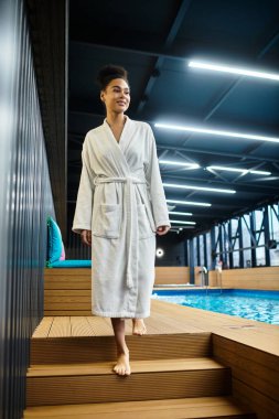 Güzel, genç bir kadın çıplak ayakla huzurlu bir havuza doğru yürüyor, rahatlık ve neşe somutlaştırıyor..