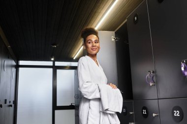 Spa bornozlu güzel bir kadın rahatlama ve refahı karşılarken gülümsüyor..