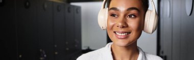 Güzel, Afro-Amerikalı bir kadın, sakin bir spa ortamında dinlenirken müzik dinliyor..