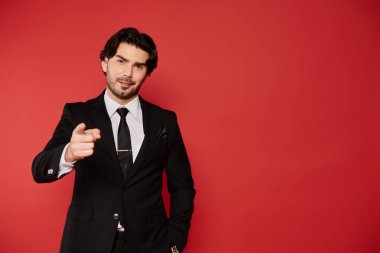 Siyah saçlı, parlak siyah takım elbiseli, kendine güvenen ve gülümseyen genç bir adam..