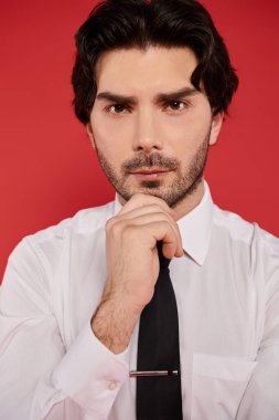 Beyaz gömlekli ve siyah kravatlı genç esmer adam düşünceli bir bakışla kendine güveniyor..
