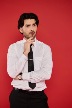 Siyah saçlı, genç, yakışıklı bir adam düşünceli, beyaz gömlekli ve siyah kravatlı..