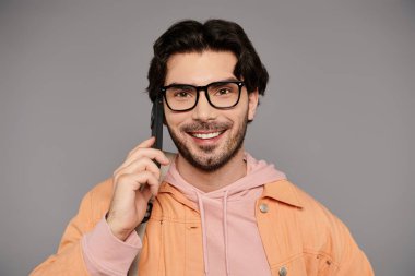 Gözlüklü esmer adam canlı bir telefon görüşmesi yaparken gülümsüyor, sıcaklık saçıyor..