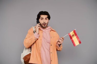 Esmer adam telefonda konuşurken ve İspanyol bayrağı sallarken şaşkınlığını dile getiriyor..