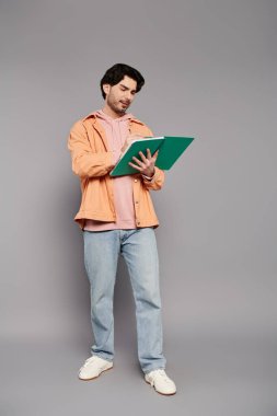 Yeşil bir klasör tutarken rahat giyinen yakışıklı genç adam kendine güveniyor..