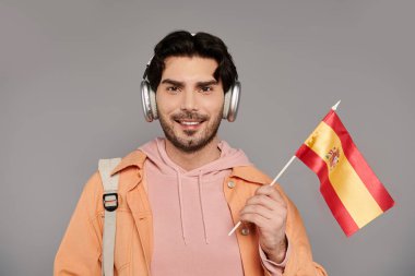 Çağdaş bir stüdyoda, genç ve yakışıklı bir adam gururla İspanyol bayrağı sallarken müziğin tadını çıkarıyor..