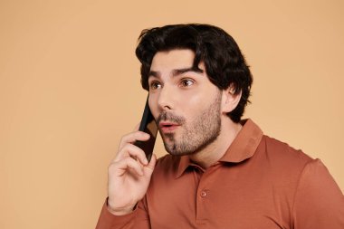Genç adam heyecanlı bir şekilde telefonda konuşuyor, canlı bir ortamda şaşkınlık gösteriyor..