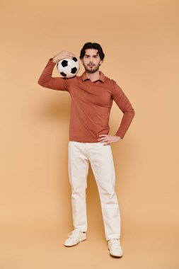 Genç bir adam bir futbol topunu kafasında dengeliyor, parlak bir stüdyoya güven saçıyor..