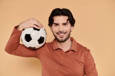 A cheerful young man holds a soccer ball on his shoulder, exuding confidence and charm. clipart