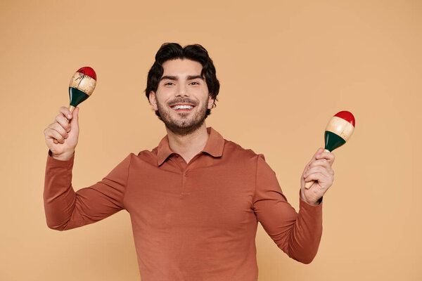 Bright atmosphere created as a handsome young man plays maracas with a cheerful smile.