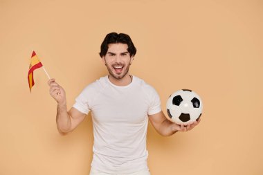 Young handsome man joyfully holds a soccer ball while waving a flag, showcasing team spirit. clipart