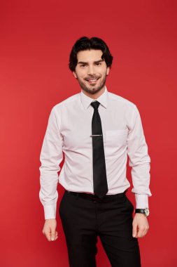 Kendine güveni tam bir genç adam. Gömlek ve kravat takıyor. Önünde parlak bir şekilde gülümsüyor..