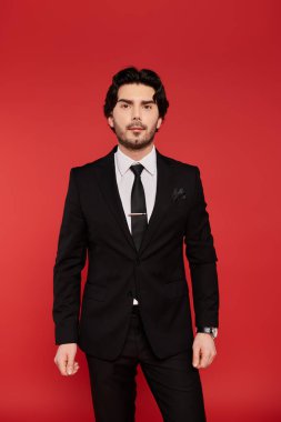 Siyah takım elbiseli siyah saçlı genç bir adam, cazibesi ve kendine güveni var..