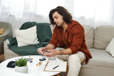 Şık bir dairede, genç bir adam kan şekerini ölçmeye odaklanır ve rutinini gösterir..