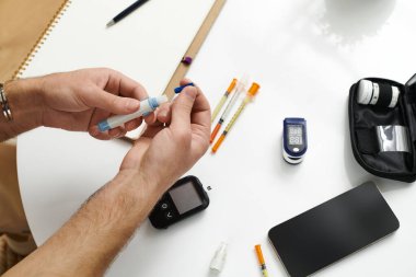 A young man with diabetes checks his blood sugar and prepares his insulin routine at home. clipart