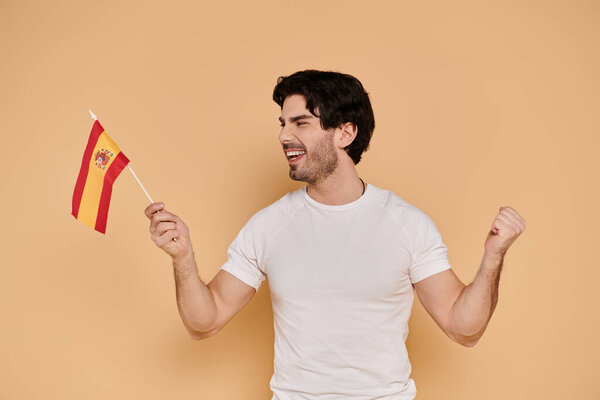 Молодой человек радостно машет маленьким испанским флагом, наполненным гордостью за свое наследие.