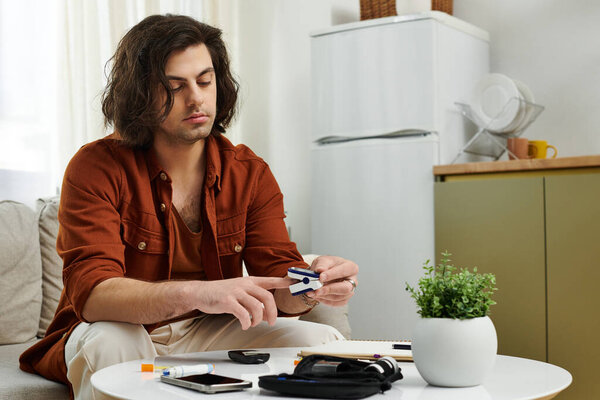Дома молодой человек с диабетом проверяет уровень сахара в крови, сохраняя здоровье..