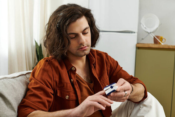 Молодой человек проверяет уровень сахара в крови при здоровой жизни в стильной домашней обстановке.