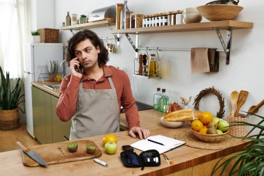 Genç adam evde şık bir mekanda sağlıklı yemekler hazırlarken diyabetini kontrol ediyor..