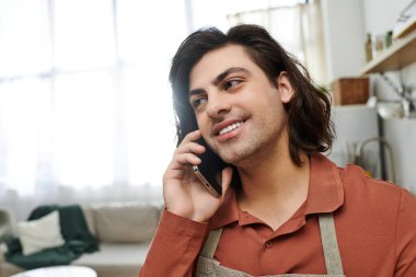 Bright apartment with a young man chatting on the phone, highlighting his lifestyle. clipart