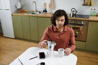 Young man prepares his morning coffee while managing diabetes in his stylish kitchen. clipart