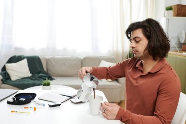 Şeker hastası bir adam şık bir dairede günlük sağlığına odaklanarak kahve yapar..