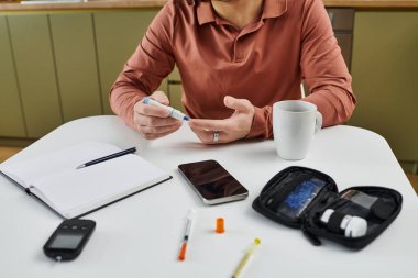 A young man monitors his blood sugar while enjoying daily life at home, demonstrating resilience. clipart