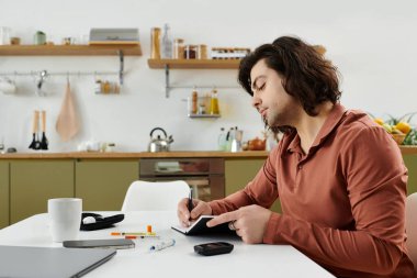 Uzun saçlı, beyaz bir adam modern bir apartman masasında sağlık alışkanlıklarını takip ediyor..
