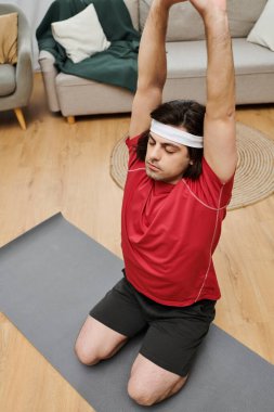 Formda bir genç adam günlük antrenman rutinini modern dairesinde yapıyor, atletizm yayıyor..