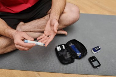 A young man manages his diabetes at home, maintaining his health routine thoughtfully and calmly. clipart